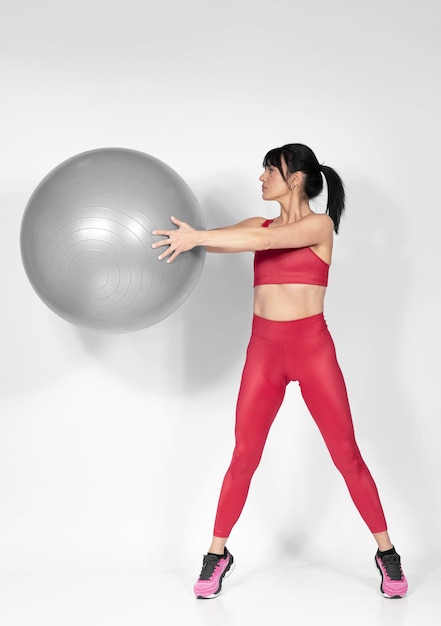 Beautiful fit woman in middle 40 doing exercises with Pilates ball studio shot