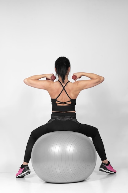 Beautiful fit woman in middle 40 doing exercises with Pilates ball studio shot