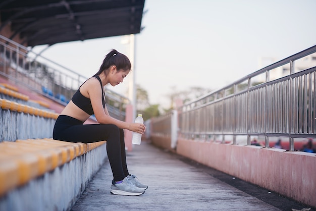 La bella donna della tenuta dell'atleta di forma fisica innaffia dopo risolve