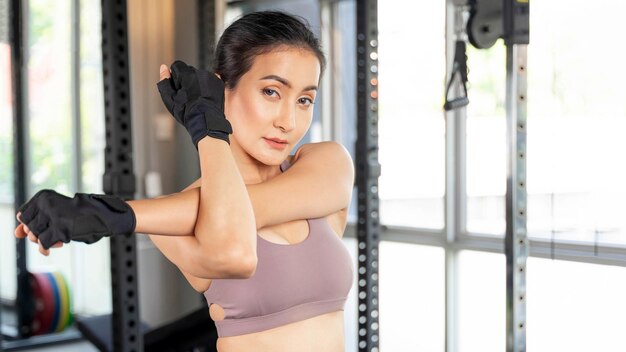 Фото Красивая фитнес-женщина в спортивной одежде, вытягивающая руку в тренажерном зале. азиатская сексуальная девушка, стройное тело, образ жизни, здоровая женщина, концепция фитнеса