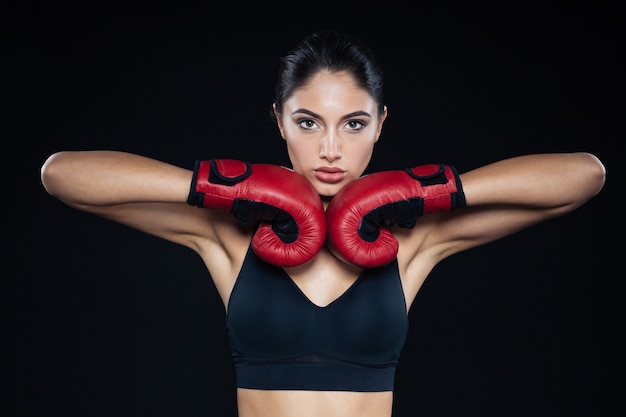 Beautiful fitness woman posing with bloxing gloves on black background