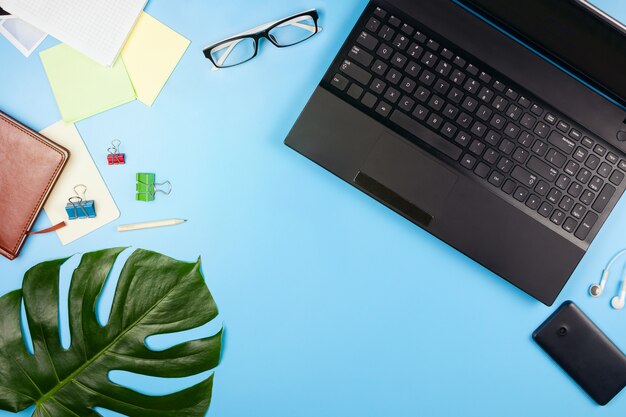 Beautiful flatlay with a laptop, glasses, philodendron leaves and other business accessories. Concept of a home office. Flat lay.