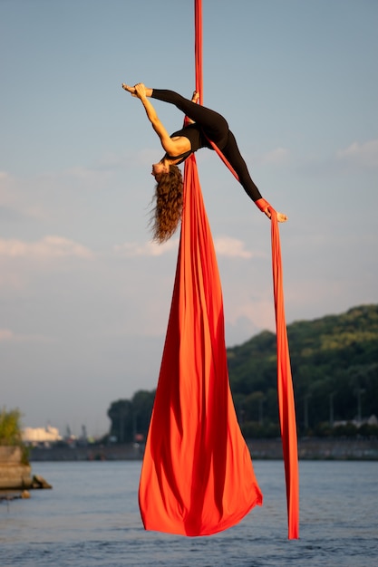 Beautiful and flexible female circus artist dancing with aerial silk