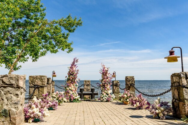 Beautiful floral composition for an away wedding ceremony on the ocean coast. Solemn ceremony of painting the groom and bride