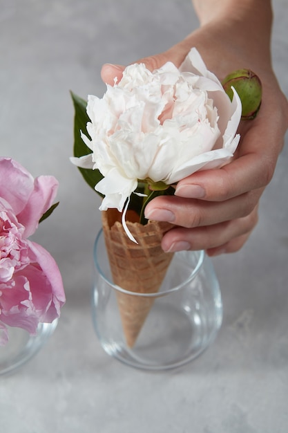 Beautiful flower in a wafer horn on a gray concrete background