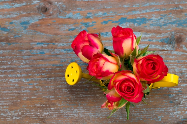 Photo beautiful flower in watering can on grunge wooden table.with copy space.the top view.