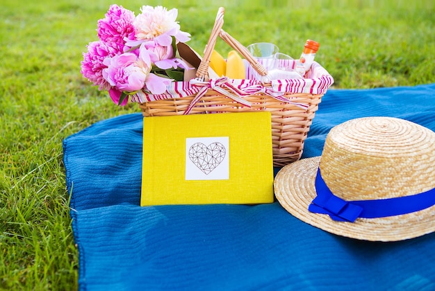 Beautiful flowers in a basket and yellow album lie on the grassbright picnic