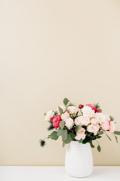 Красивый букет цветов в кашпо перед бледно-пастельно-бежевой стеной