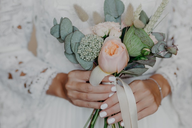 Beautiful flowers in brides hands. Woman in wedding white dress prepared for wedding ceremony.