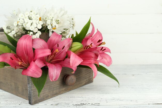 Beautiful flowers in crate on wooden background