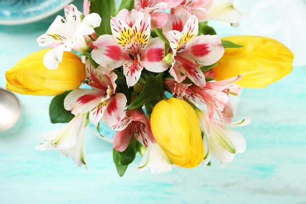 Beautiful flowers in cup on color wooden background