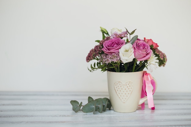 Beautiful flowers in cup on wooden