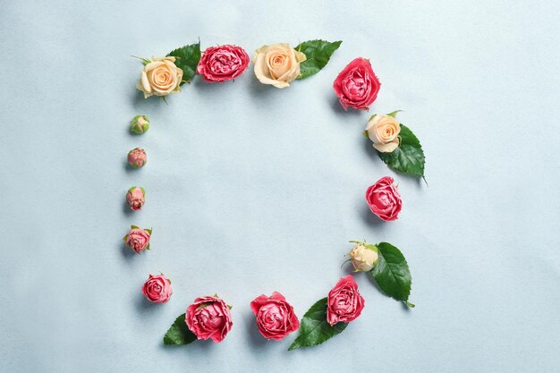 Beautiful flowers and green leaves as floral frame on light background