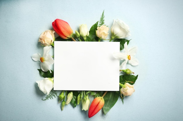 Beautiful flowers and green leaves as floral frame and paper card on light background