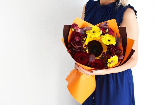 休日のための美しい花屋内で手に美しい花を持つ女性の背景フラワー ショップの花の花束