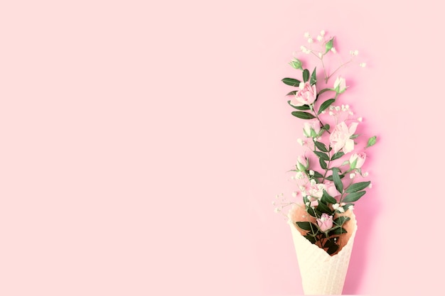 Beautiful flowers in ice cream cone on pink background. Flat lay