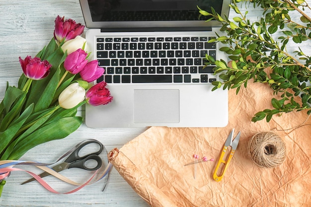 Photo beautiful flowers and laptop on florist's workplace