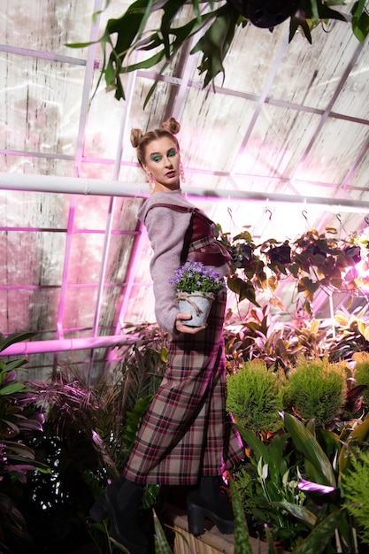 Beautiful flowers. Nice attractive woman holding a flower pot while being in the greenhouse