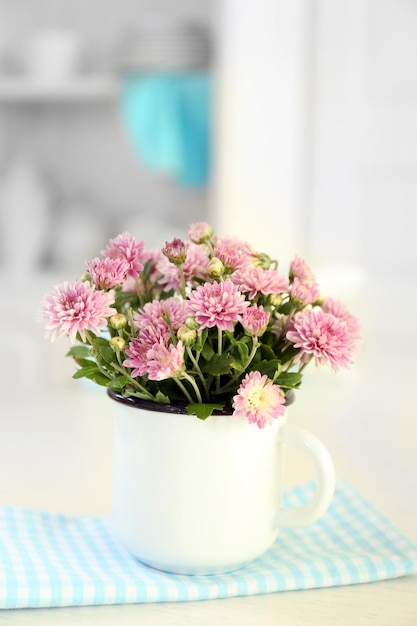 Beautiful flowers in vase on table on light background