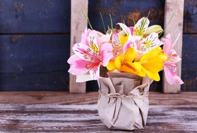 Beautiful flowers in vase on wooden background