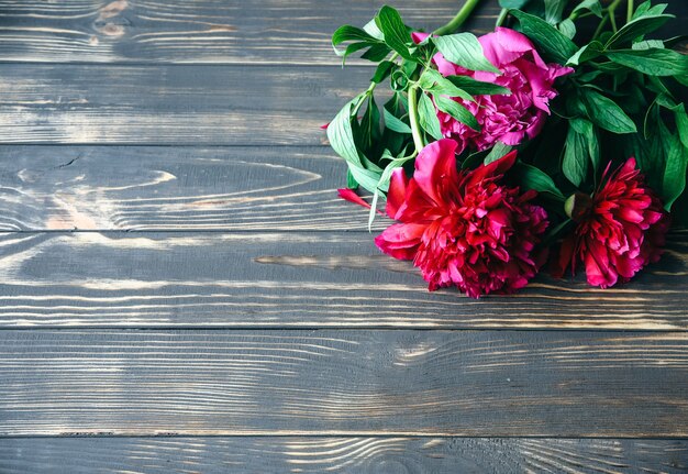 Beautiful flowers on wooden background. Peonies bouquet. Perfect flat lay with petals. Happy mother's holiday postcard. International women's day greeting. Stylish idea for advert or promotion.