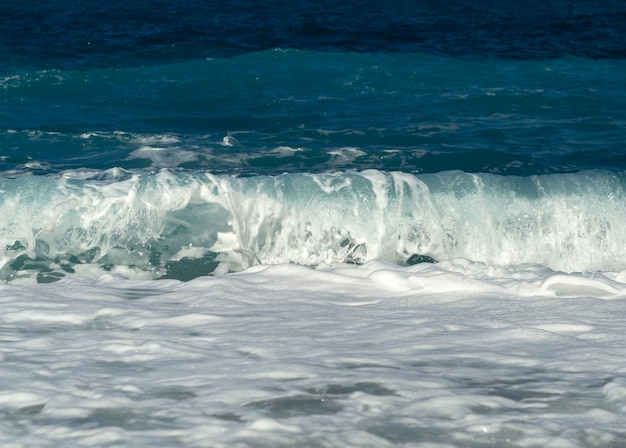 Foto belle onde di schiuma in una giornata di sole nel mar egeo sull'isola di evia in grecia