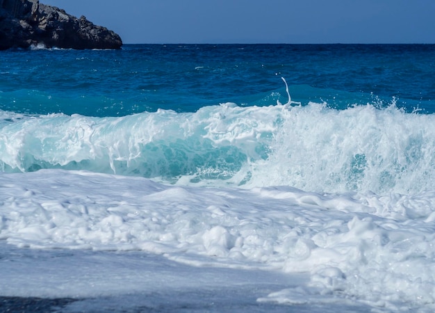 Beautiful foam waves on a sunny day in the Aegean Sea on the island of Evia in Greece