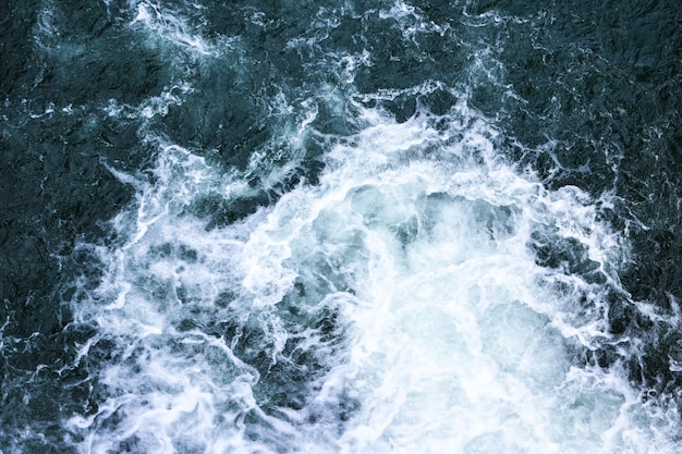 Beautiful foamy sea. Water flowing from the open sluice gates of dam. The blue sea water with spray. The texture of the waves