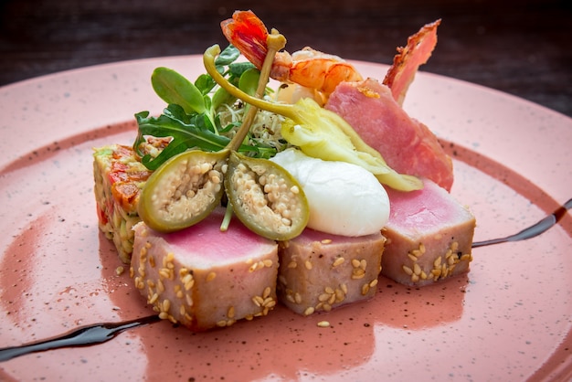 Красивая еда: стейк из тунца в кунжуте, лайме и свежий салат крупным планом на тарелке на столе.