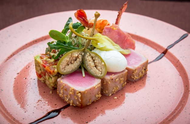 Красивая еда: стейк из тунца в кунжуте, лайм и свежий салат крупным планом на тарелке