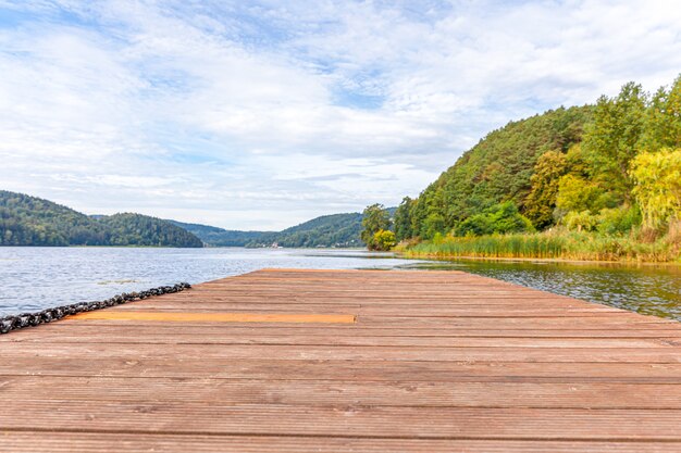Beautiful forest lake or river on sunny summer day and old rustic wooden dock or pier