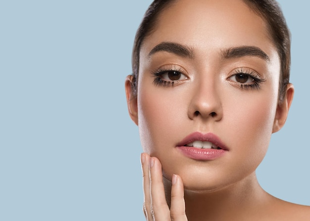 Foto belle lentiggini donna bruna capelli ritratto pelle sana toccando il viso. colore di sfondo blu