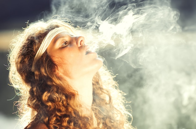 Beautiful free hippie girl blowing smoke