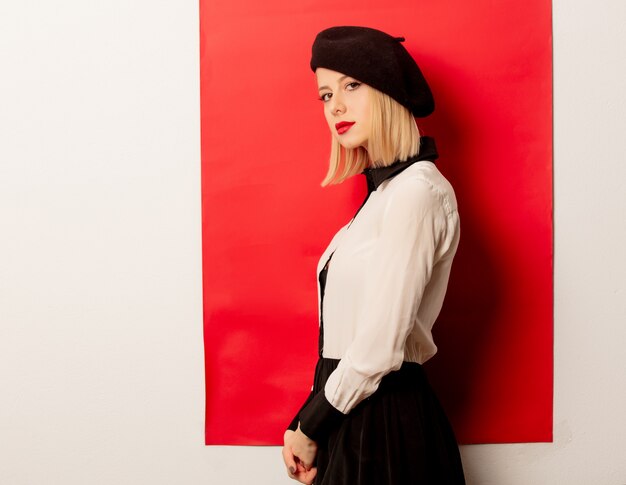 Beautiful french woman in beret on red wall