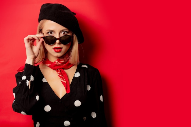 Beautiful french woman in beret on red wall