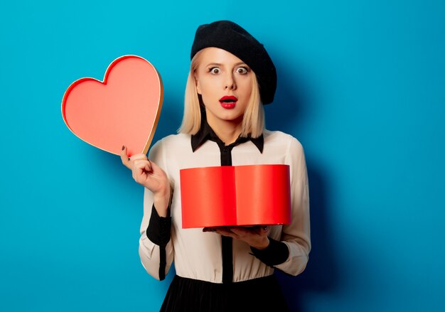 Beautiful french woman in beret with heart shape gift box