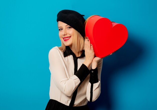 Beautiful french woman in beret with heart shape gift box