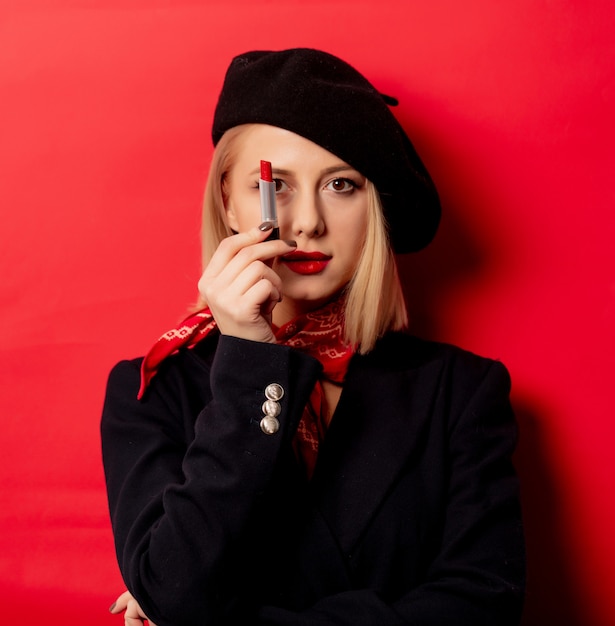 Beautiful french woman in beret with lipstick on red wall