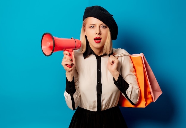 Beautiful french woman in beret with shopping bags and  loudspeaker