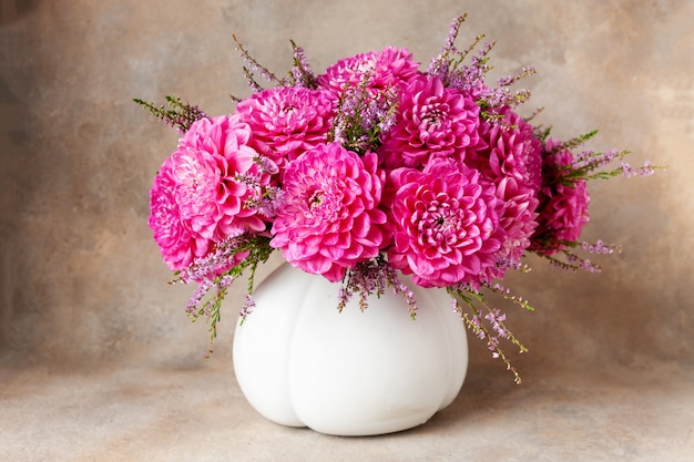 Beautiful fresh bouquet of pink dahlias in white vase.