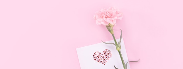 Beautiful, fresh elegant carnation flower bouquet with white greeting thanks gift card isolated on bright pink color background, top view, flat lay concept.