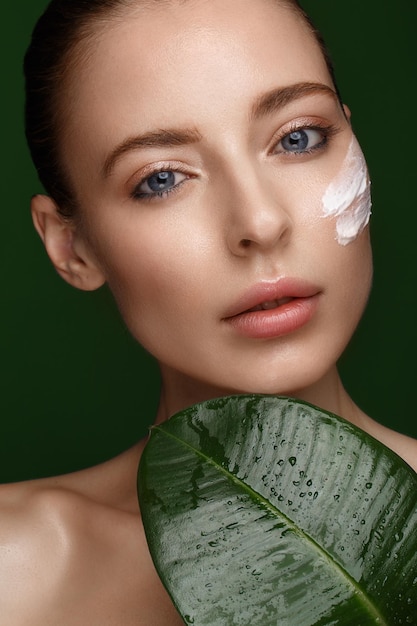 Bella ragazza fresca con trucco naturale della pelle perfetta e foglie verdi bellezza viso