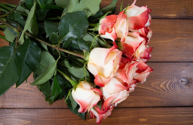 写真 美しい新鮮な大きな赤とベージュのバラは、木製の茶色の背景に横たわっています