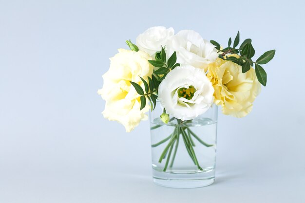 Beautiful fresh modern bouquet of eustoma in transparent glass vase with copy space