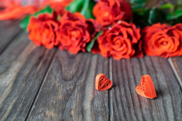 写真 木材に2つの小さなクイルドハートの美しい新鮮な赤いバラ