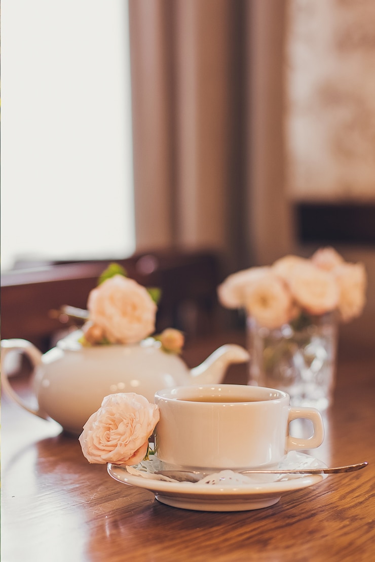 Photo beautiful fresh roses near a cup of tea and a in pastel tones romantic mood.