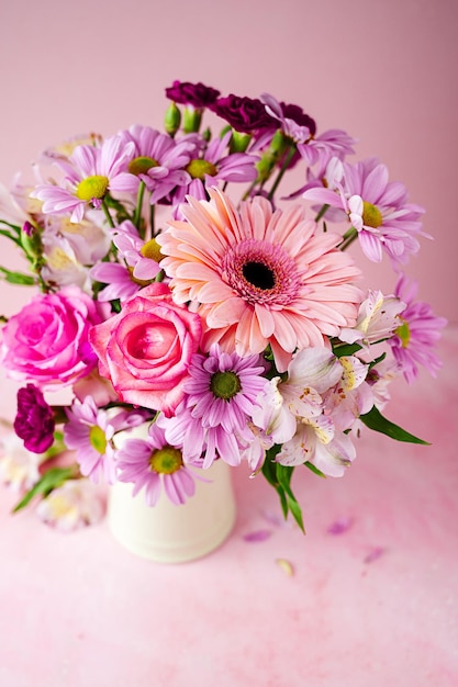 Beautiful fresh spring flowers Pink bouquet of flowers in vase on pink background