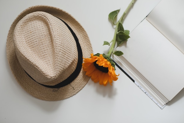 beautiful fresh sunflower and a straw hat and a book top view