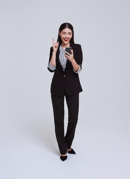 Beautiful and friendly face Asian businesswoman smile in formal suit holding mobile phone