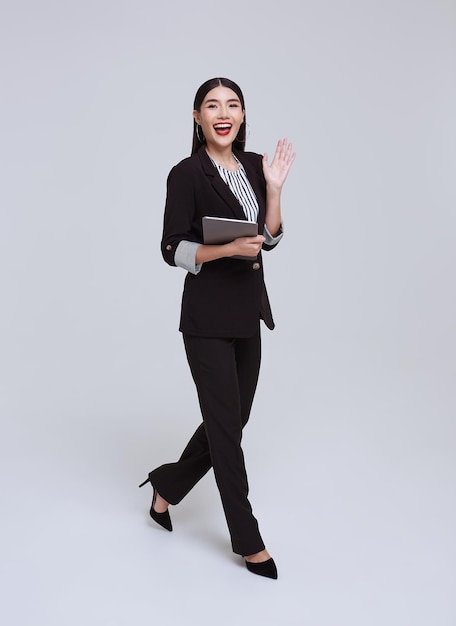 タブレットを保持しているフォーマルなスーツで美しくフレンドリーな顔のアジアの実業家の笑顔